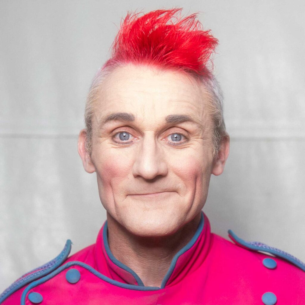 Head and shoulders photo of Tweedy with a tuft of red hair and a pink top.