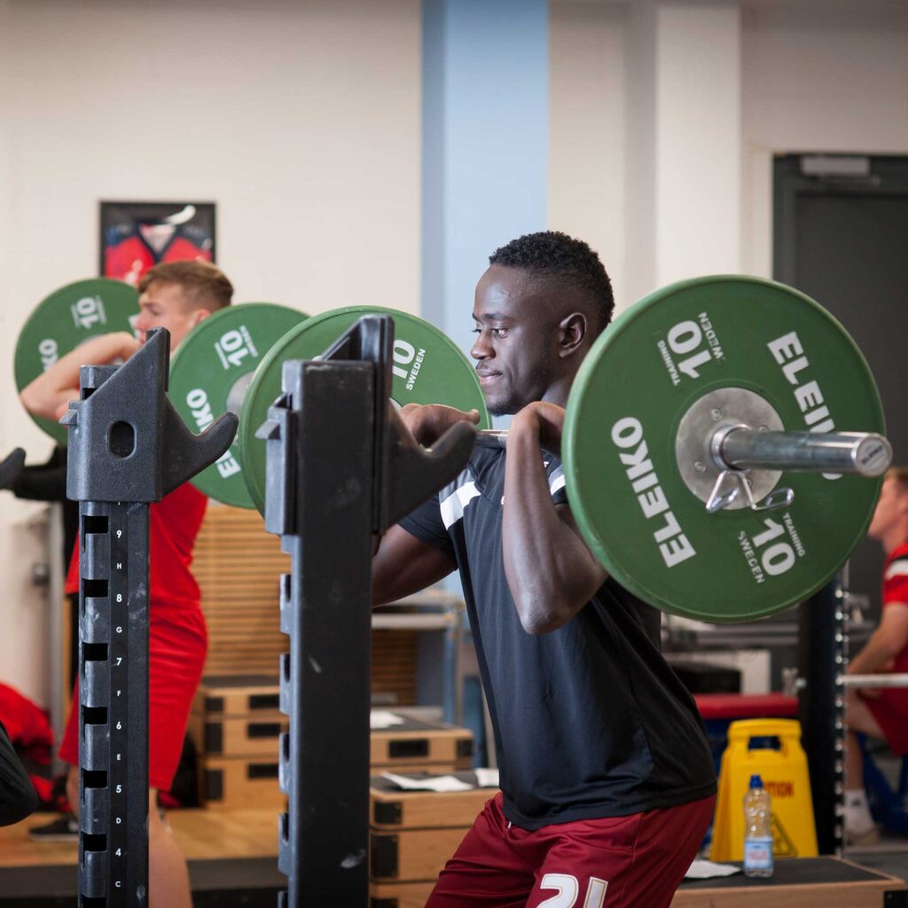 A student lifting weights in the university gym.