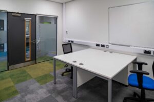 Interior of the 'incubator' meeting room showing desks and whiteboard.