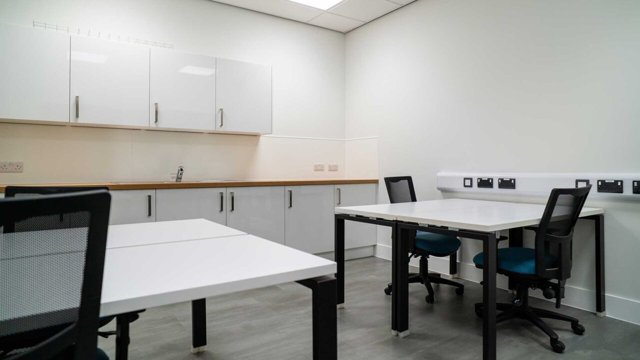 Interior of the 'incubator' meeting room showing desks and a small kitchen area.