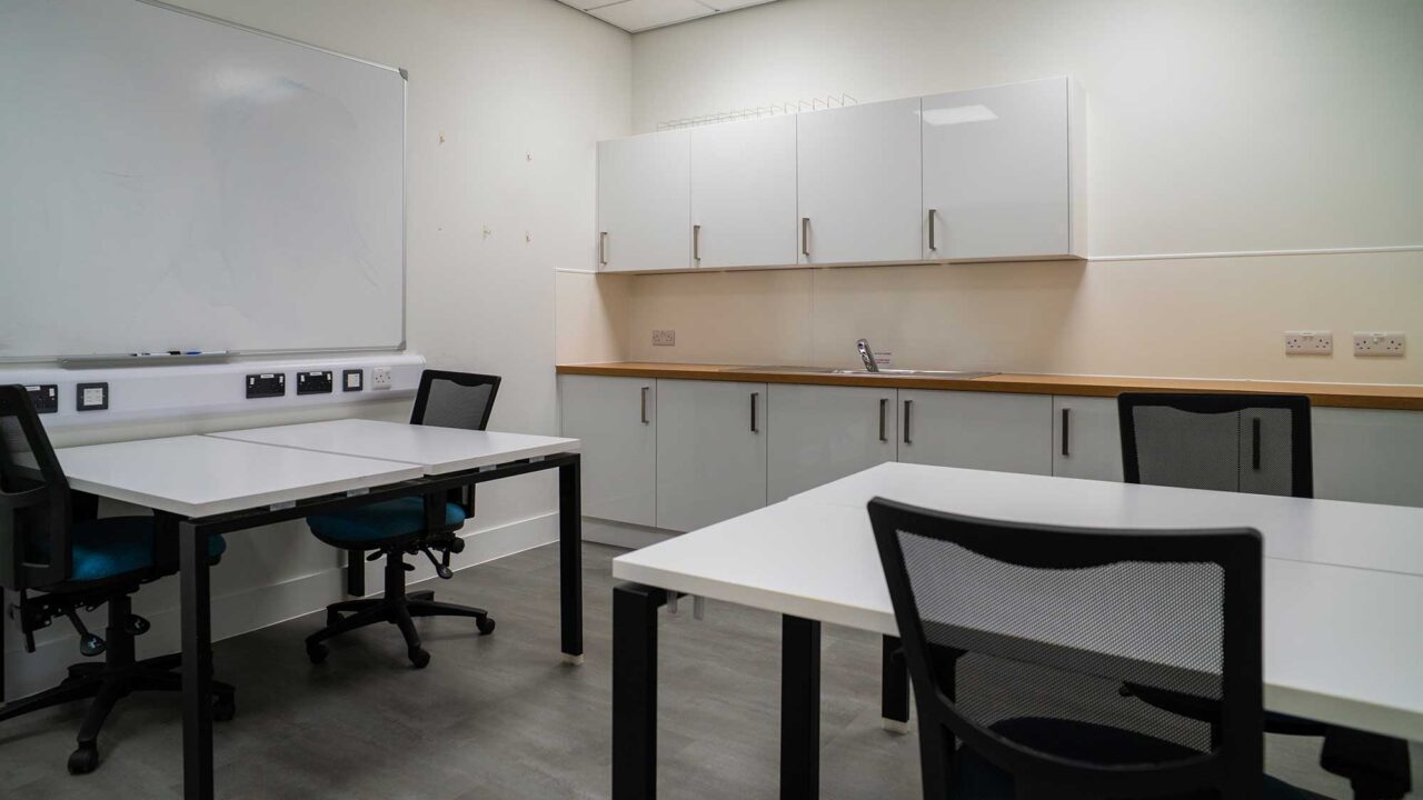 Interior of the 'incubator' meeting room showing desks and a small kitchen area.