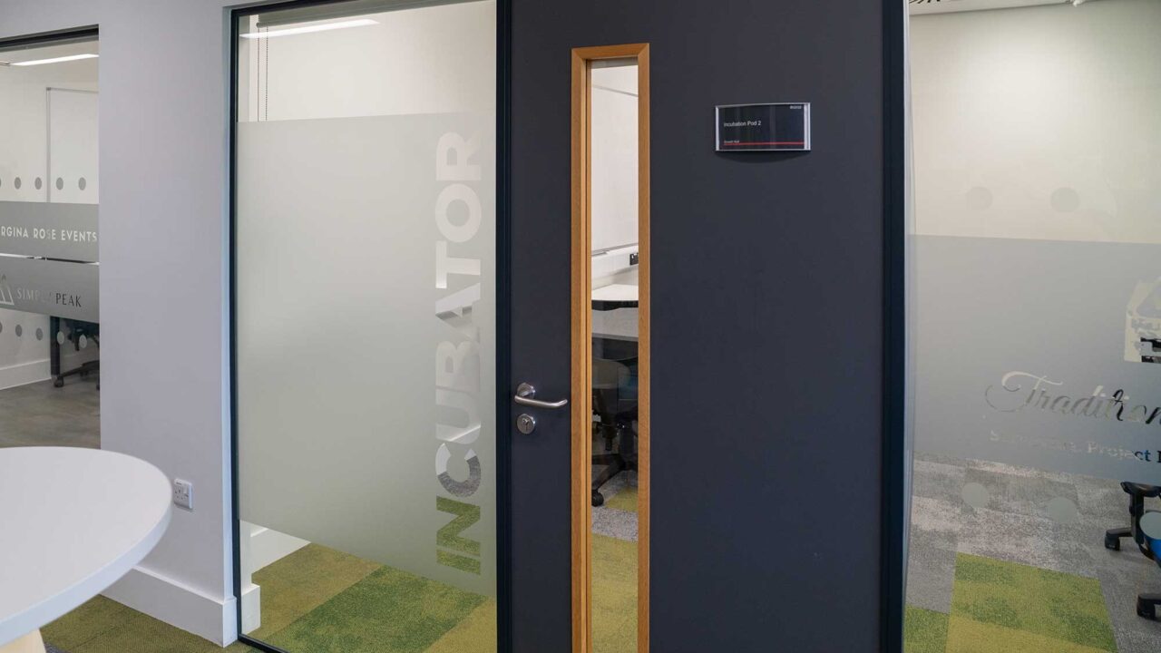 Exterior of the 'incubator' meeting room showing the door and interior glass window.