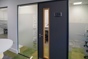 Exterior of the 'incubator' meeting room showing the door and interior glass window.