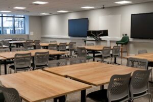 City Campus classroom set up with desks chairs and two screens on the wall.