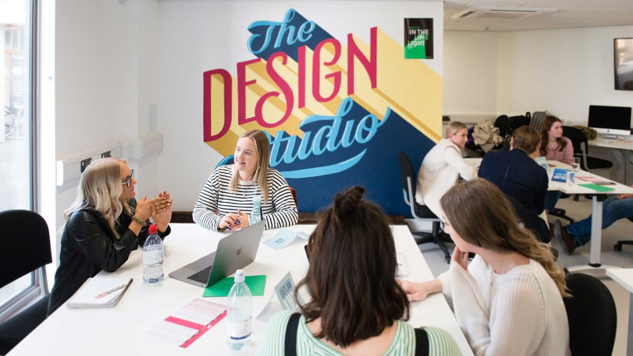 Students sit together in the design studio talking to each other.