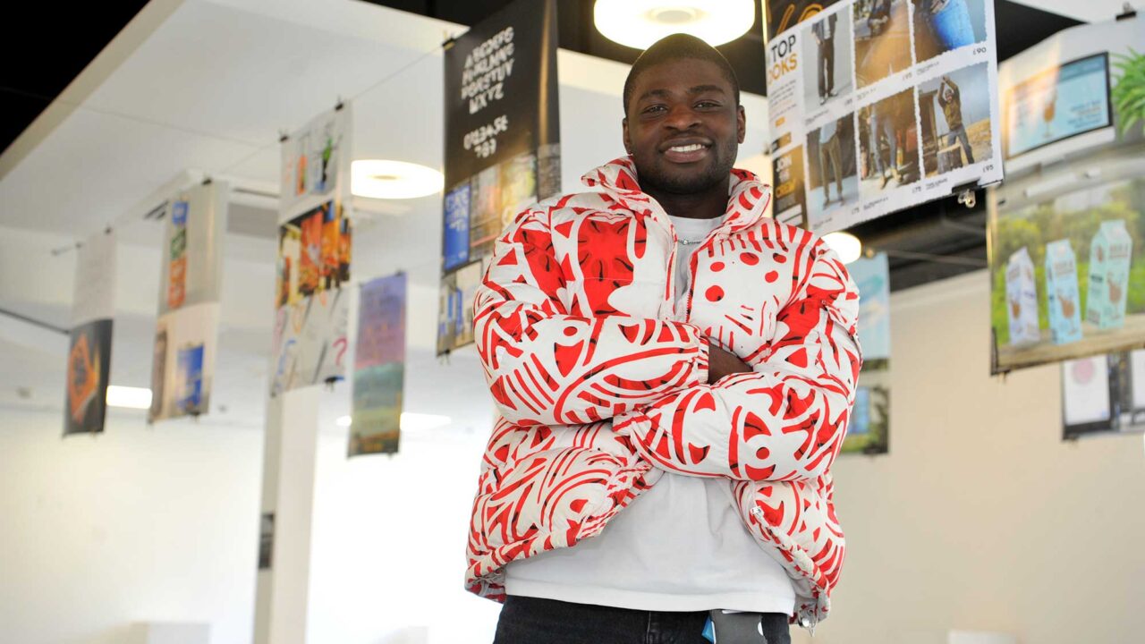 A Graphic Design student poses for a photo with his arms folded.