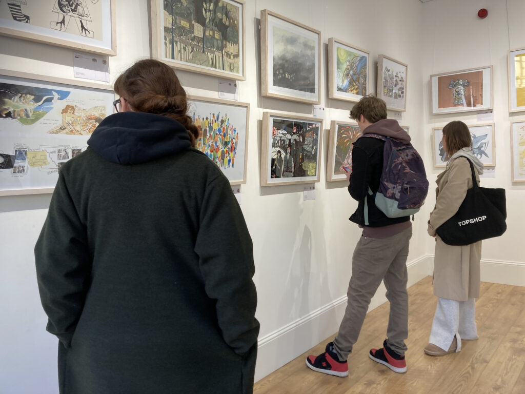 three people with their backs to the camera looking at a display of art