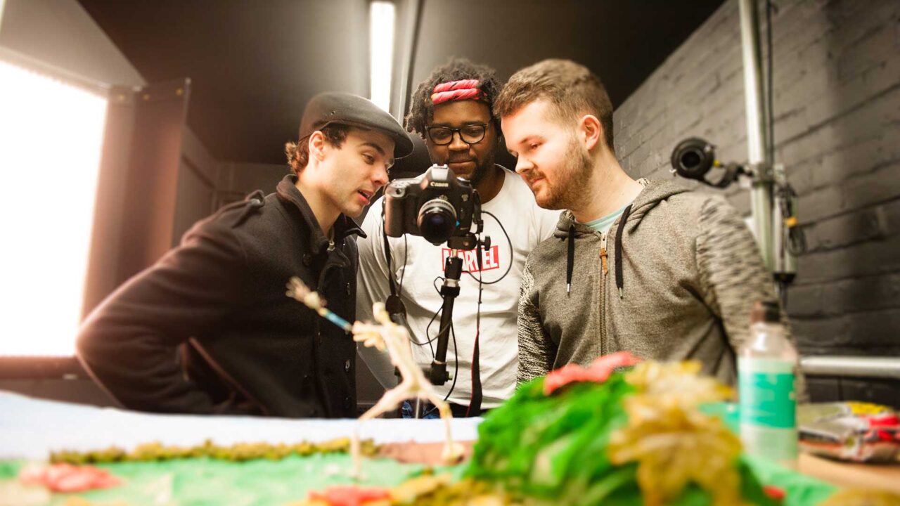 Three students use a camera in the animation studio.