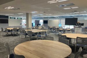 A large open-plan space showing tables, chairs and screens.