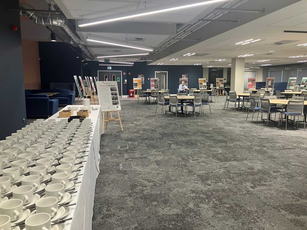 A large open-plan space showing a table with cups and saucers, and tables and chairs.