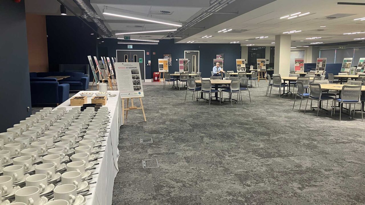 A large open-plan space showing a table with cups and saucers, and tables and chairs.