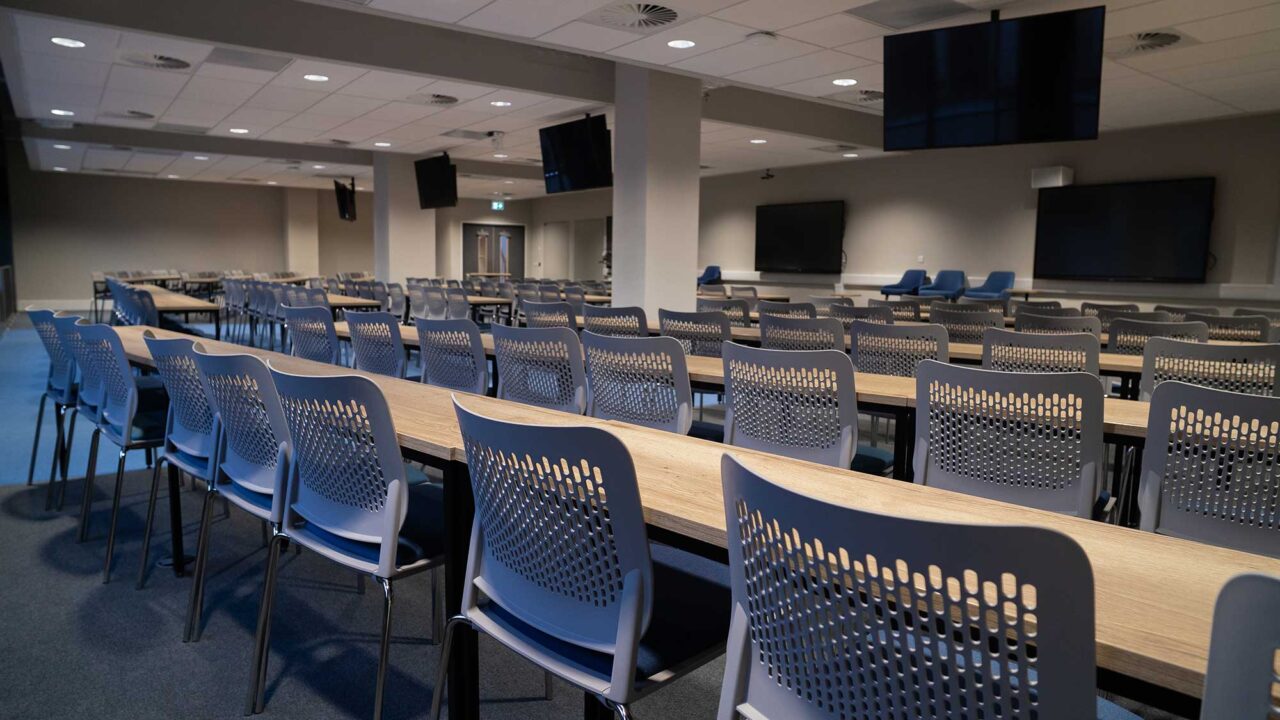 The lecture theatre at City Campus with rows of desks and numerous suspended flat screens.