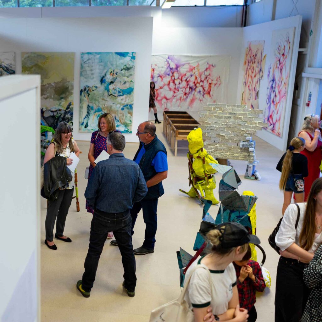 People stood looking at art work and chatting at UoG's Degree show 2025.