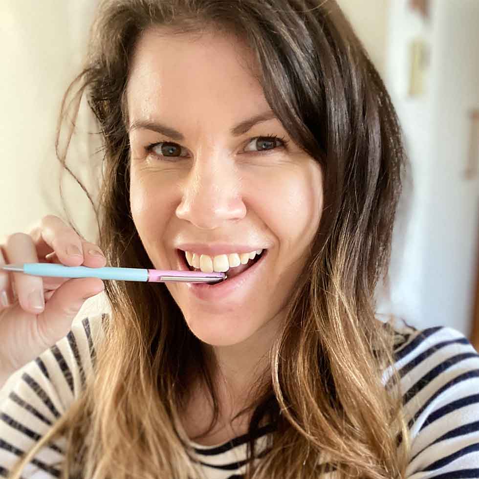 A photo of Catherine posing with a pen and smiling.