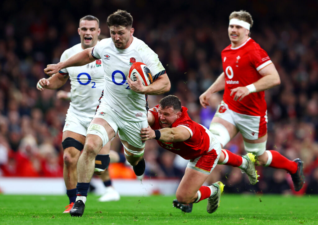 Tom Curry of England with ball in hand evades the tackle of Elliot Dee of Wales