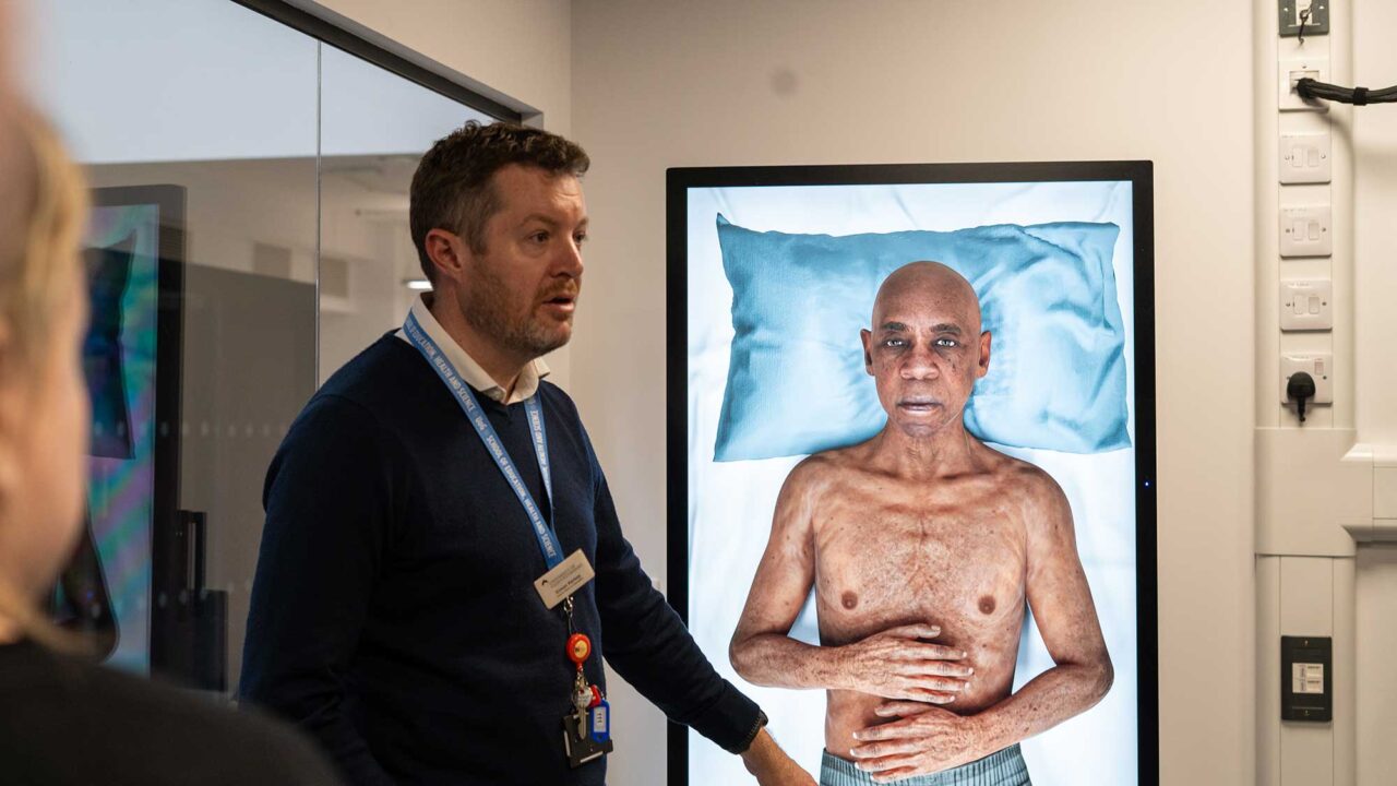 Practice Skills and Simulation Lead, Simon Kearsey, shows a simulated image of a patient lying on a bed in the FutureSIM facility.