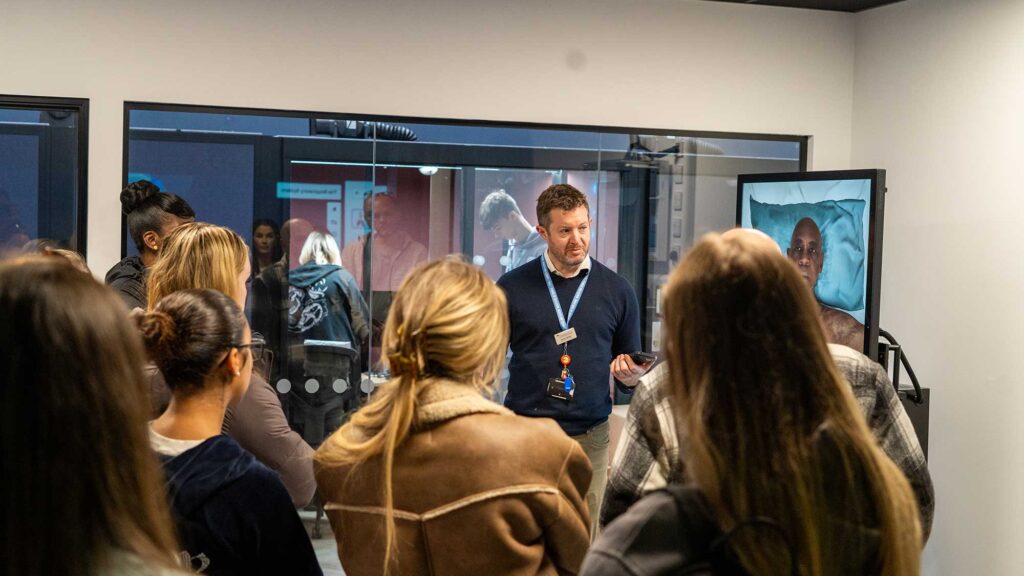 Practice Skills and Simulation Lead, Simon Kearsey, gives a presentation to a group of students in the FutureSIM facility.
