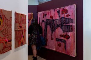 Textile blocks hanging up at the degree show with someone walking through.