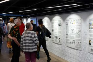 Corridor at Park Campus showing degree show work on boards and guests looking at these.
