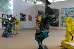Exhibition space at Park campus with sculptures made out of different materials and large canvasses displayed in the background.