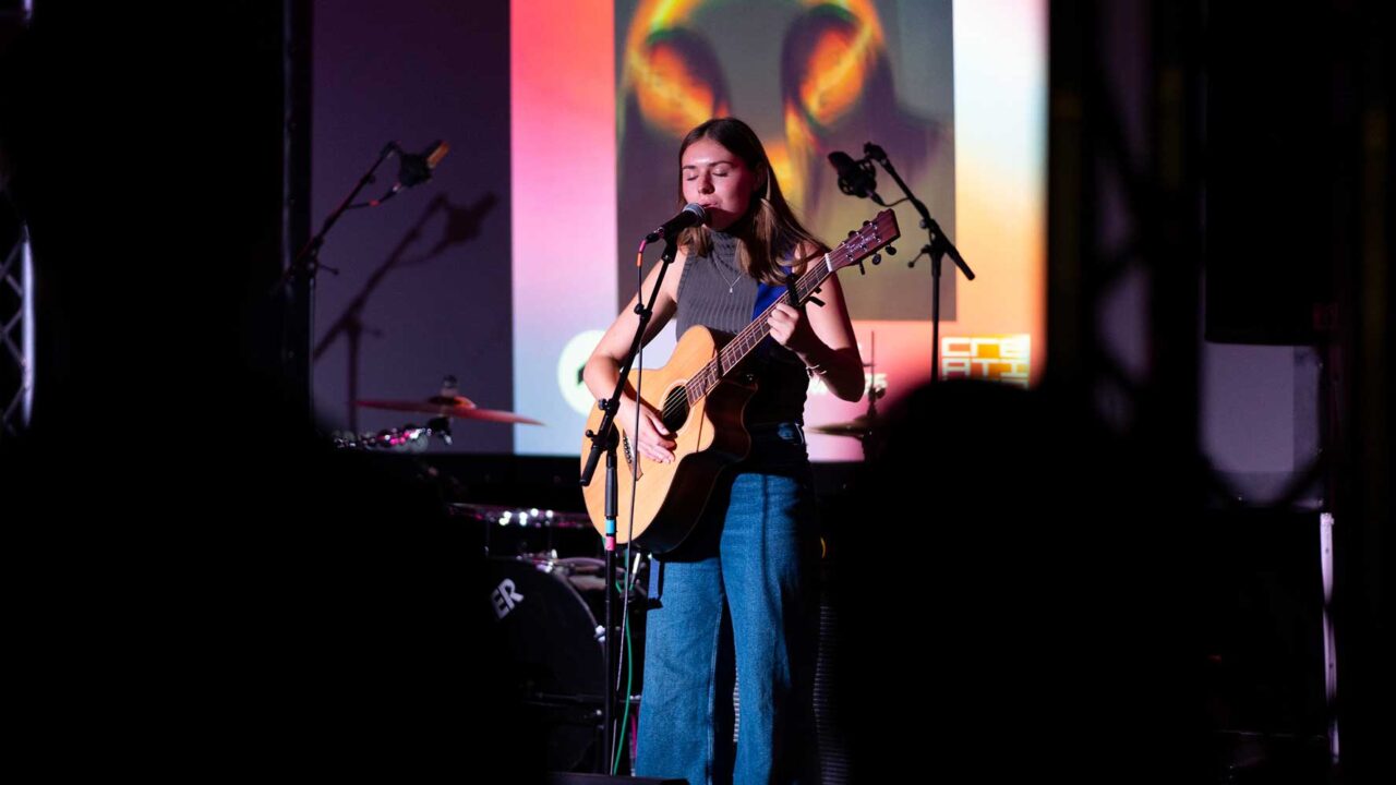 Student singing and playing guitar at the 2025 degree show.