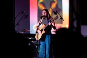 Student singing and playing guitar at the 2025 degree show.