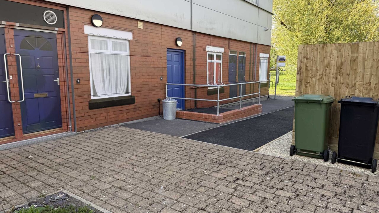 The outdoor simulation area recreates a realistic street environment with a bus stop and domestic entrances.