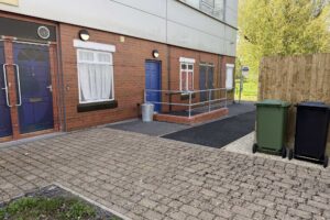 The outdoor simulation area recreates a realistic street environment with a bus stop and domestic entrances.