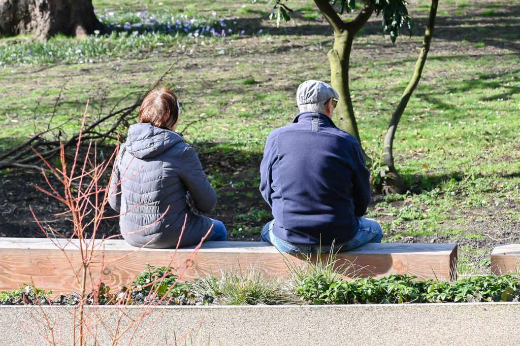 A man and a woman sitting on a bench in a park.