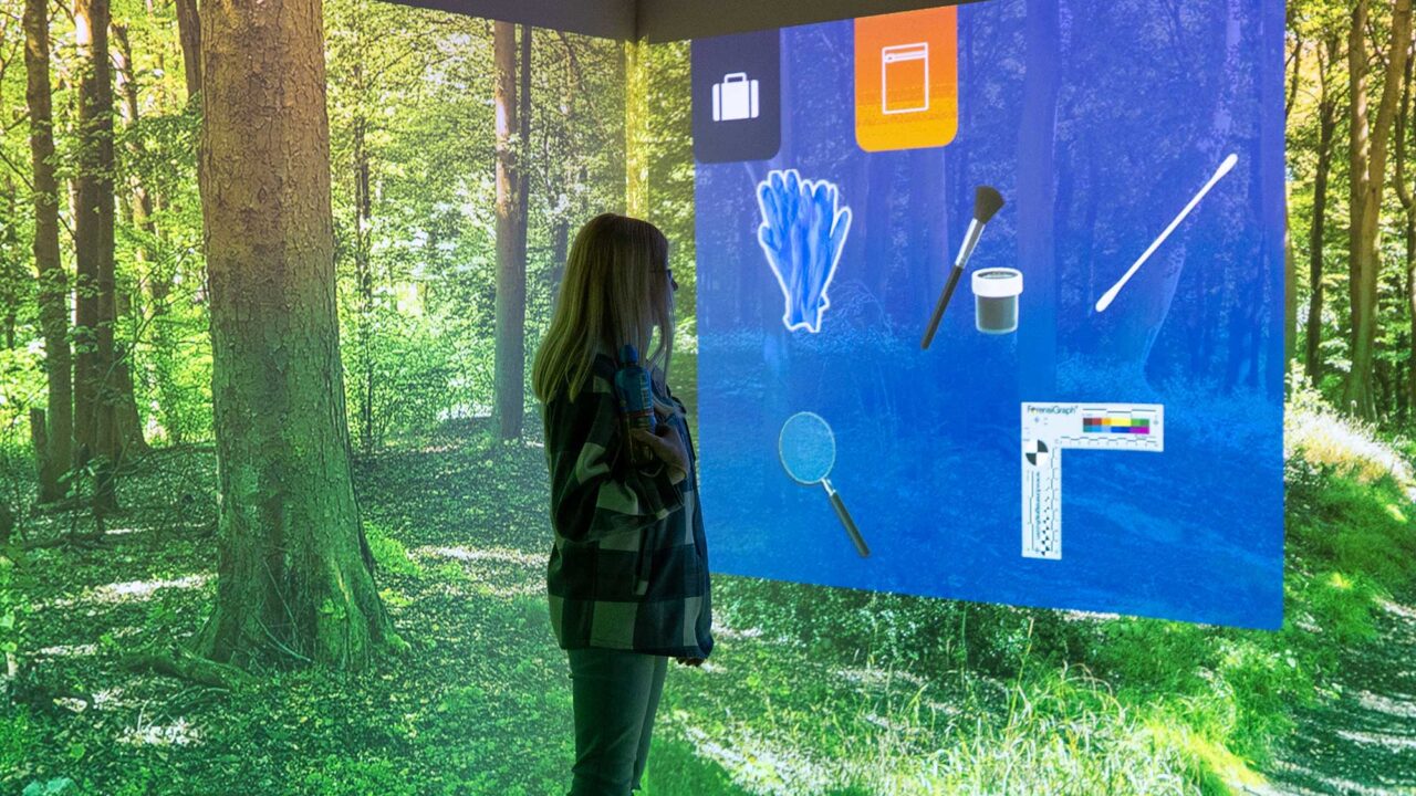 A student looks at the digital screens showing a simulated crime scene in at the FutureSim facility.
