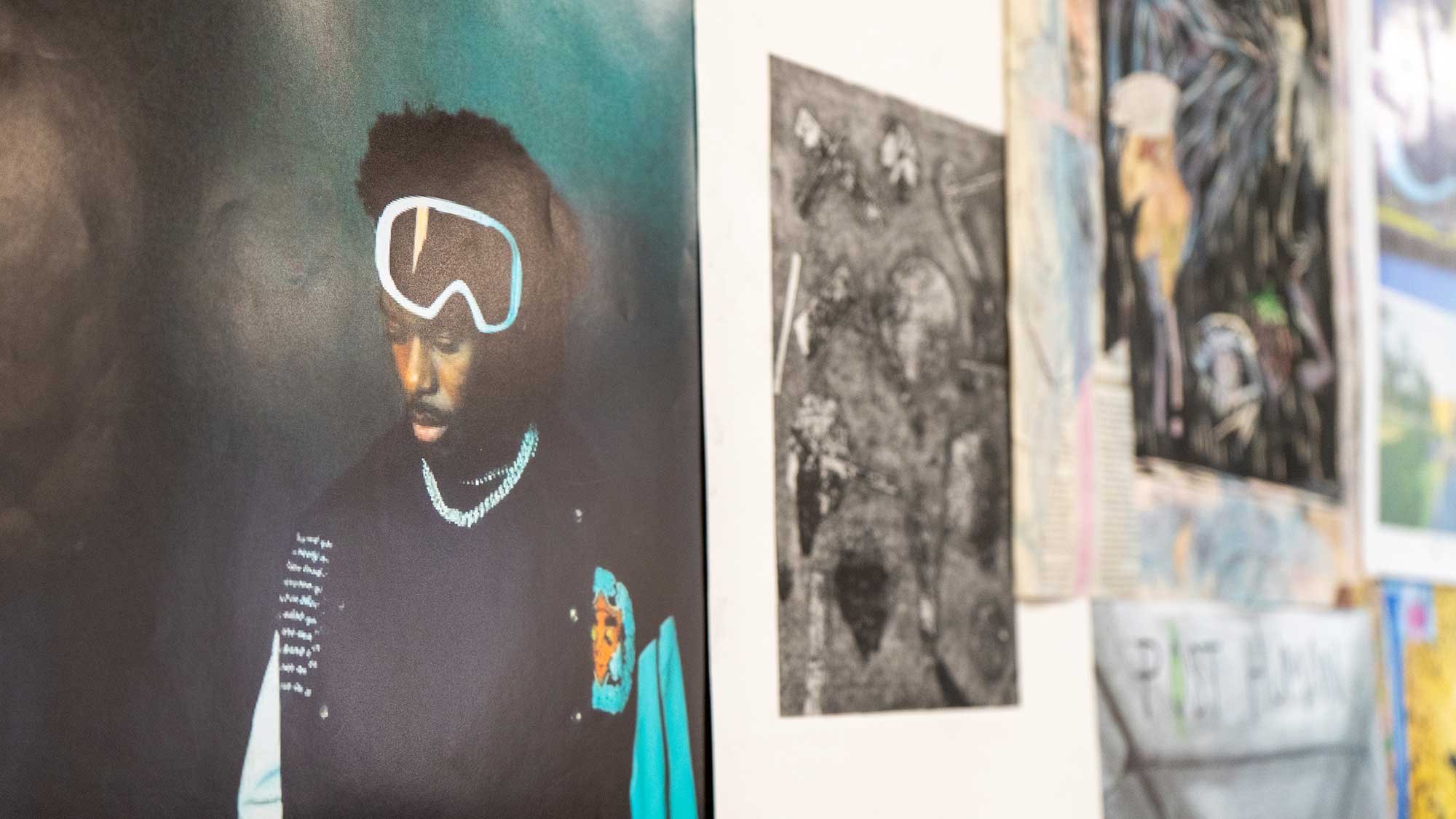 A wall in the art studio at Park Campus covered in posters and pieces of artwork.