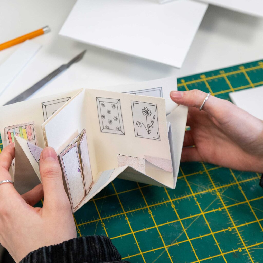 A student holding a pop-up piece of art in their hands.