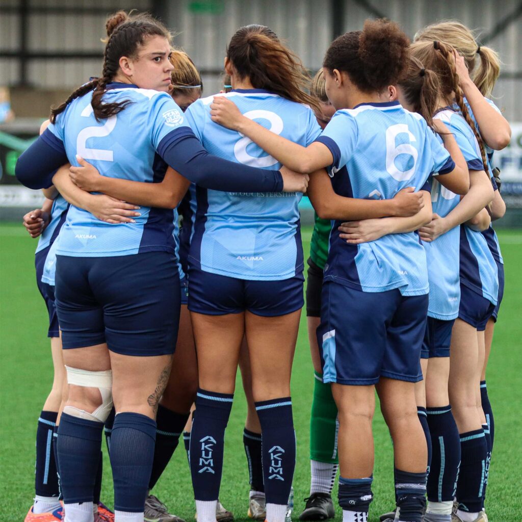 Womens football students in a huddle on the pitch