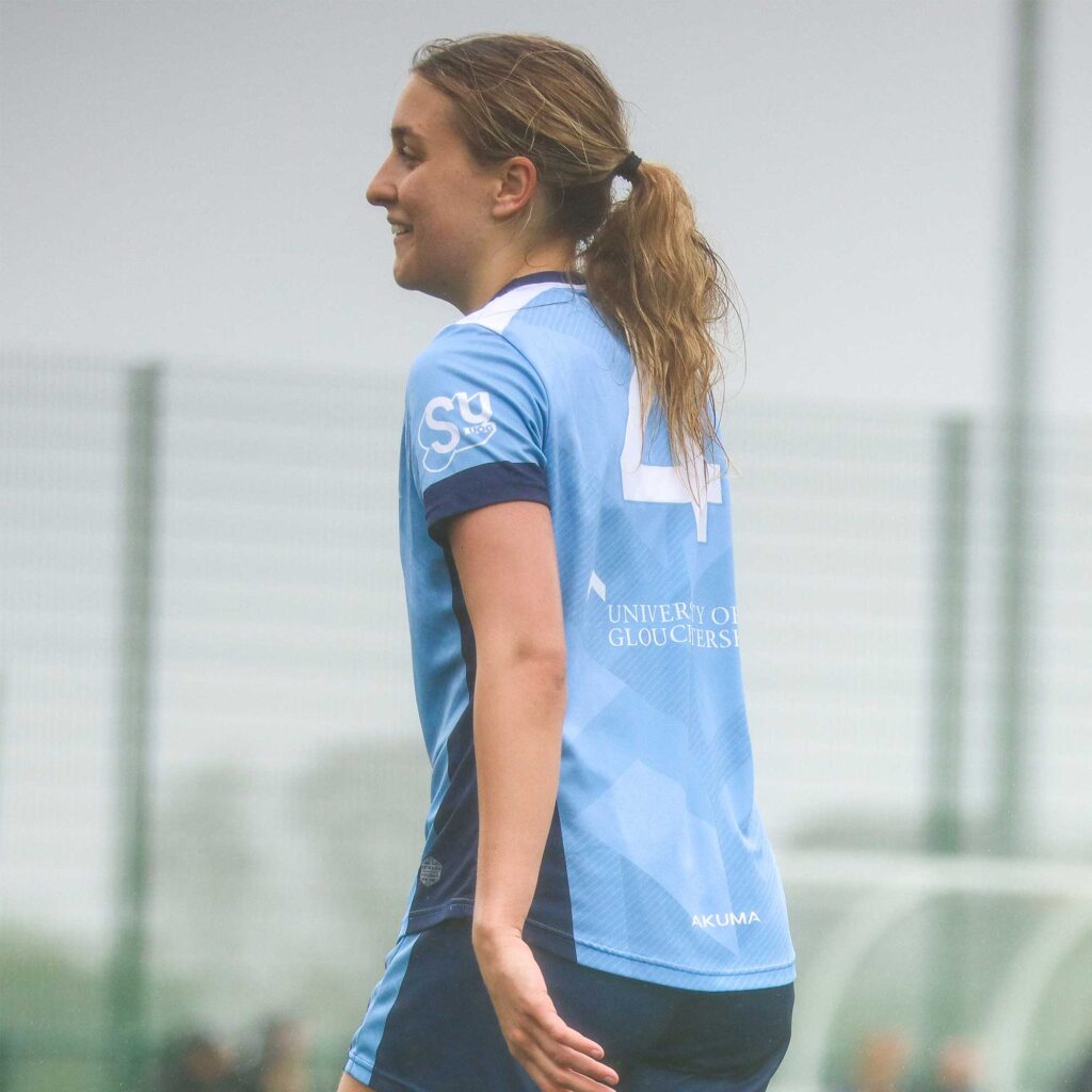Female football player wearing number 4 University of Gloucestershire kit.