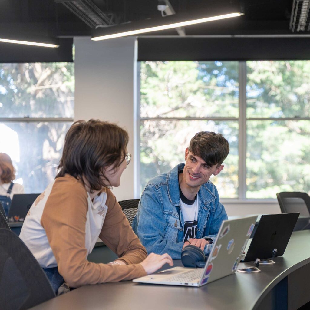 Two students talk to each other in a teaching room at Park Campus.