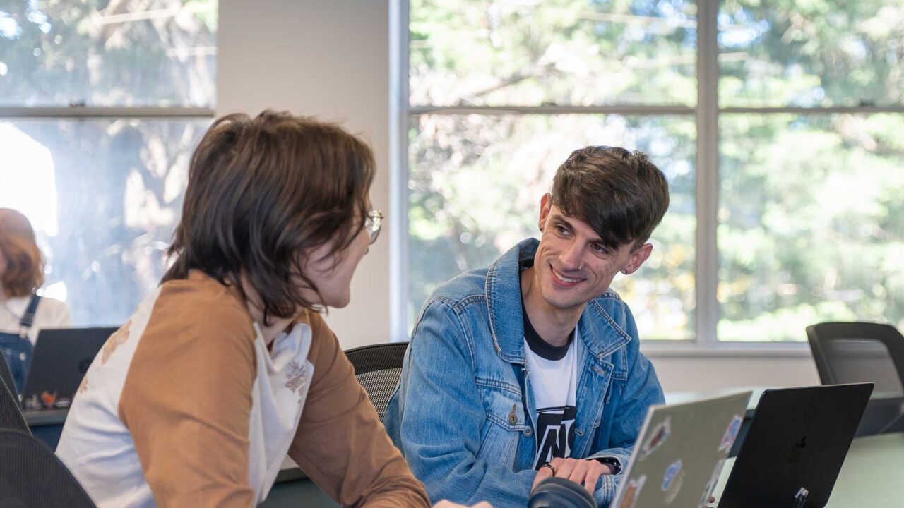 Two students talk to each other in a teaching room at Park Campus.