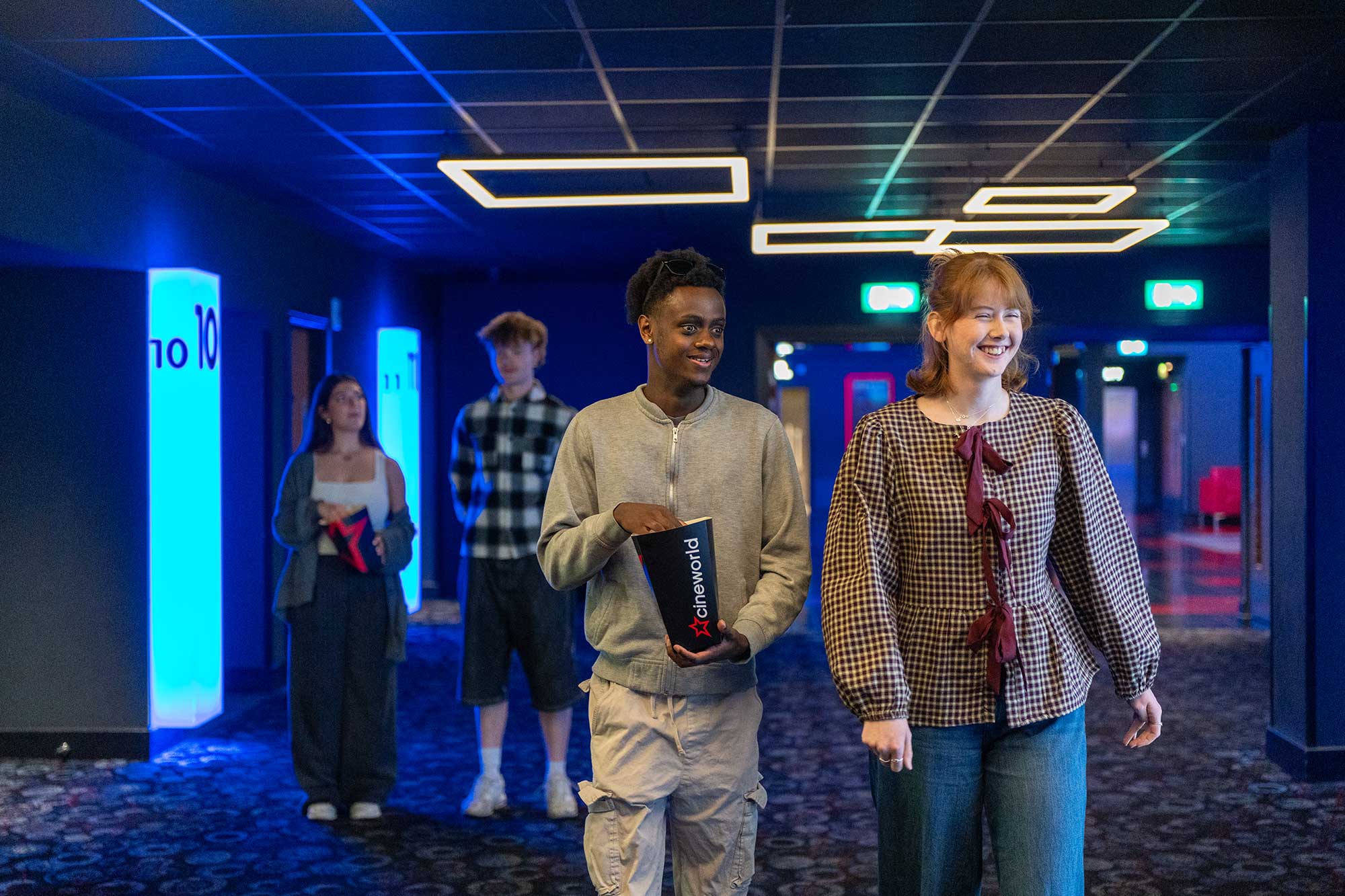 Students walking through the atrium at Cineworld holding popcorn.