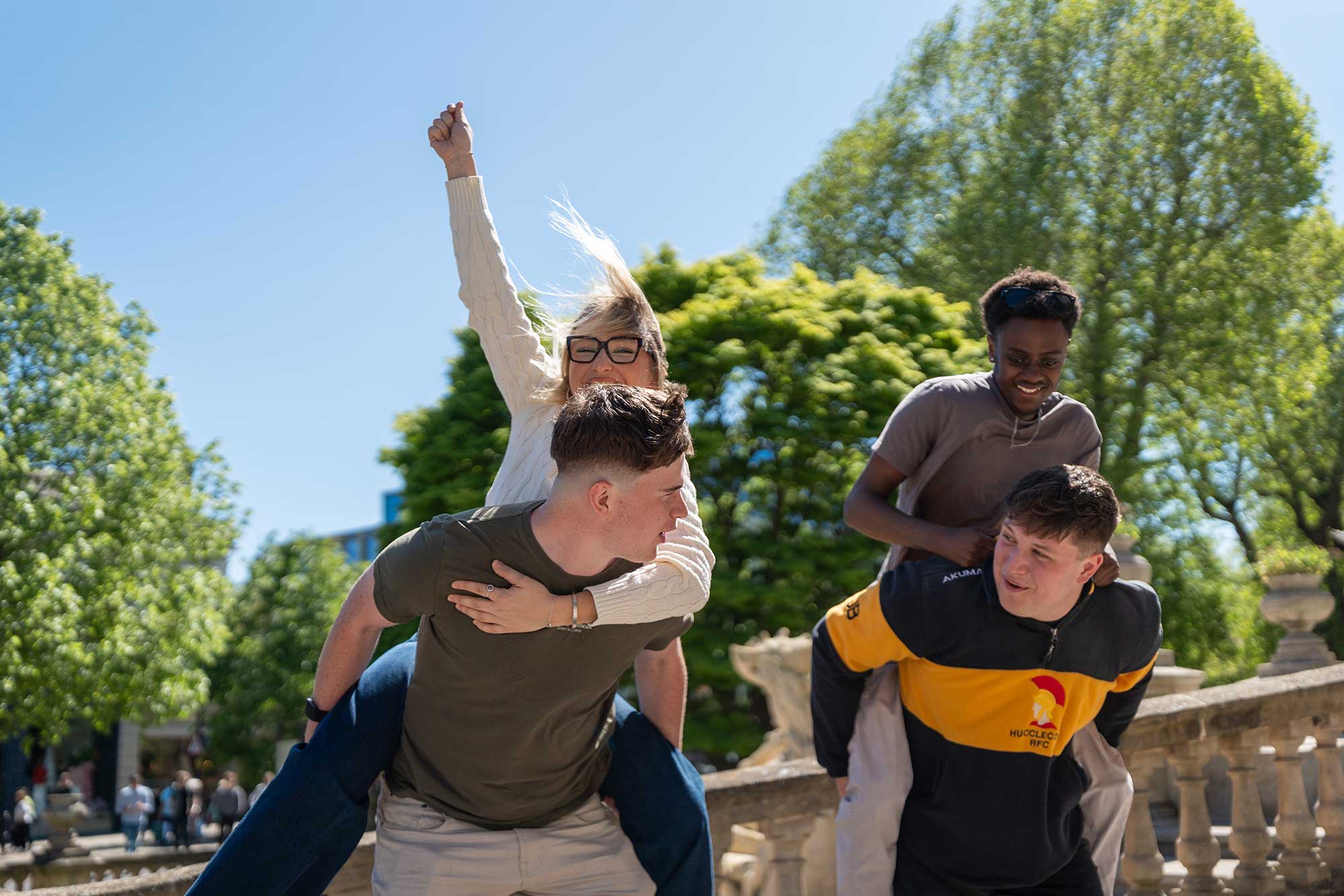 Students giving each other a piggy back, celebrating together.