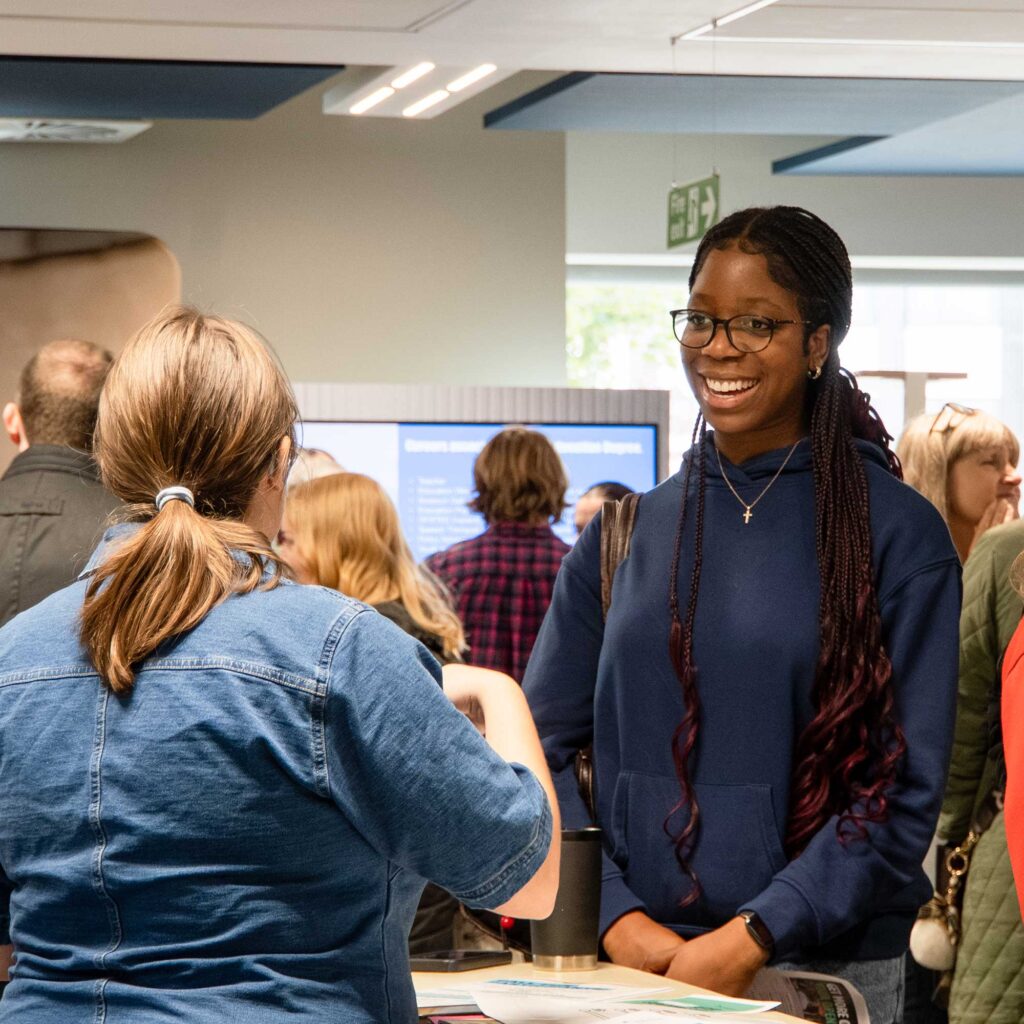 A prospective student talks to a staff member at an open day event.