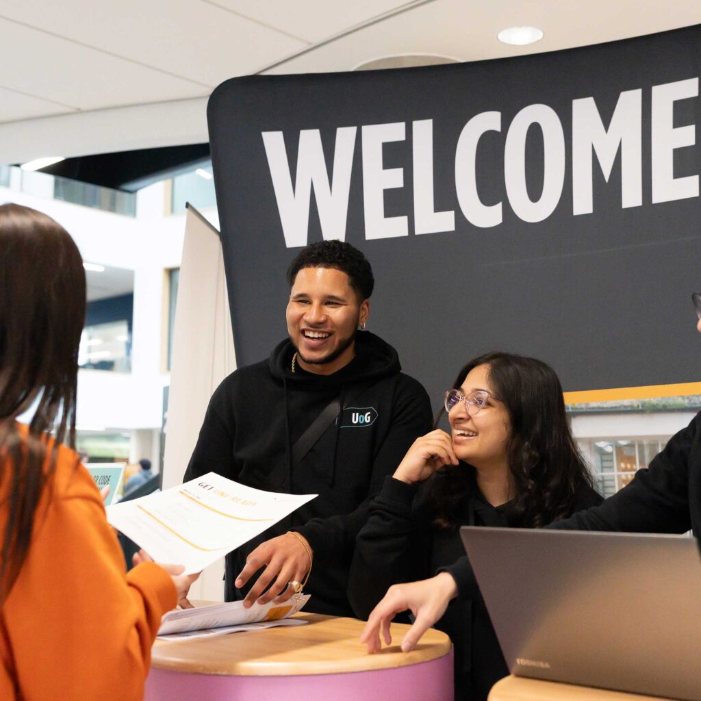 Student ambassadors greeting visitors at the welcome desk of an open event.