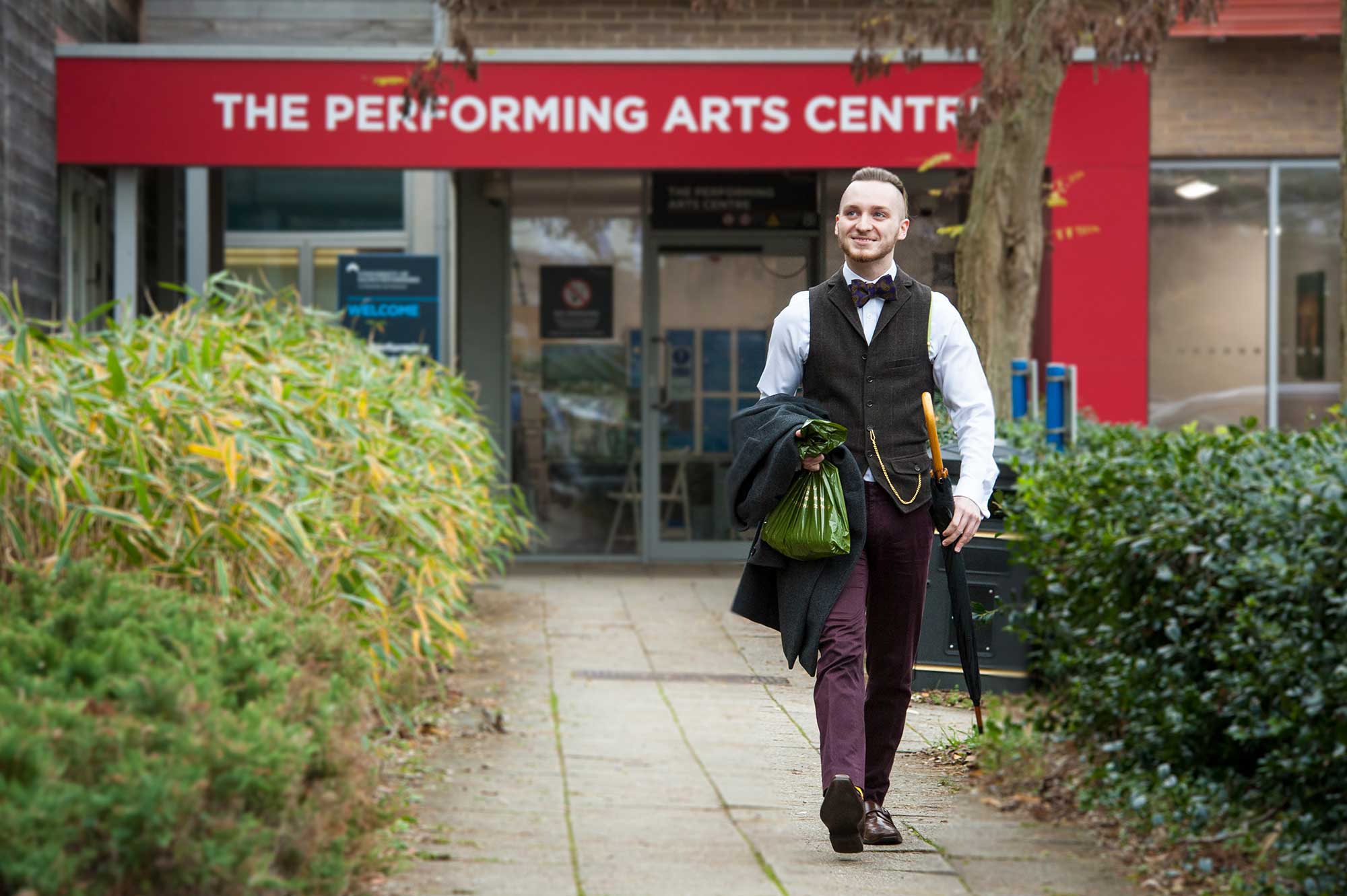A drama student walks out of the Performing Arts Centre smiling.