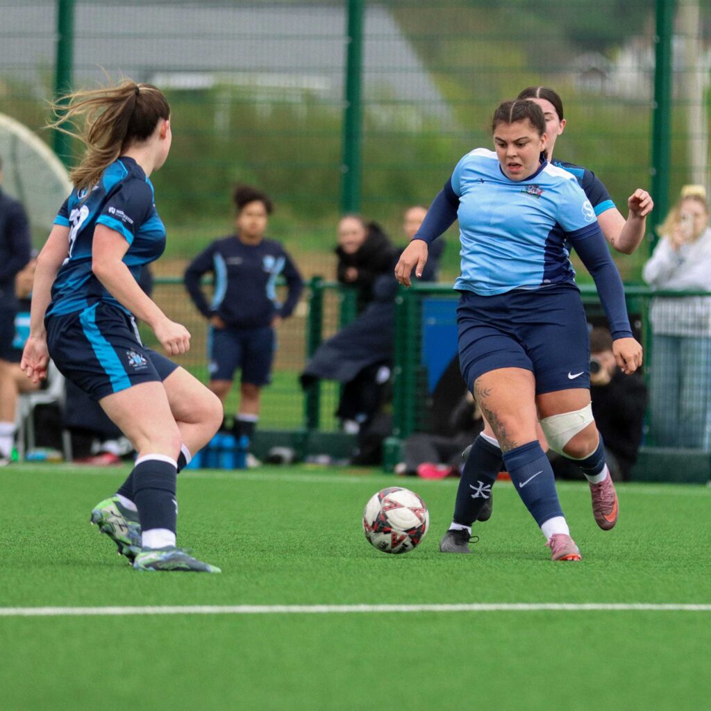 Players of Women's Football at Varsity tackling the ball on the astroturf.