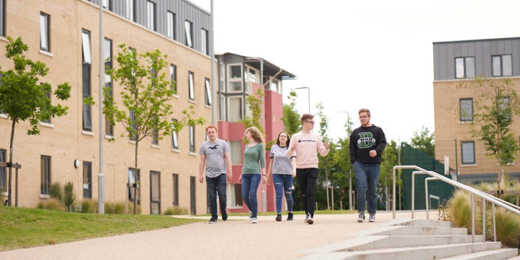 Students walking through Pittville Student Village chatting.
