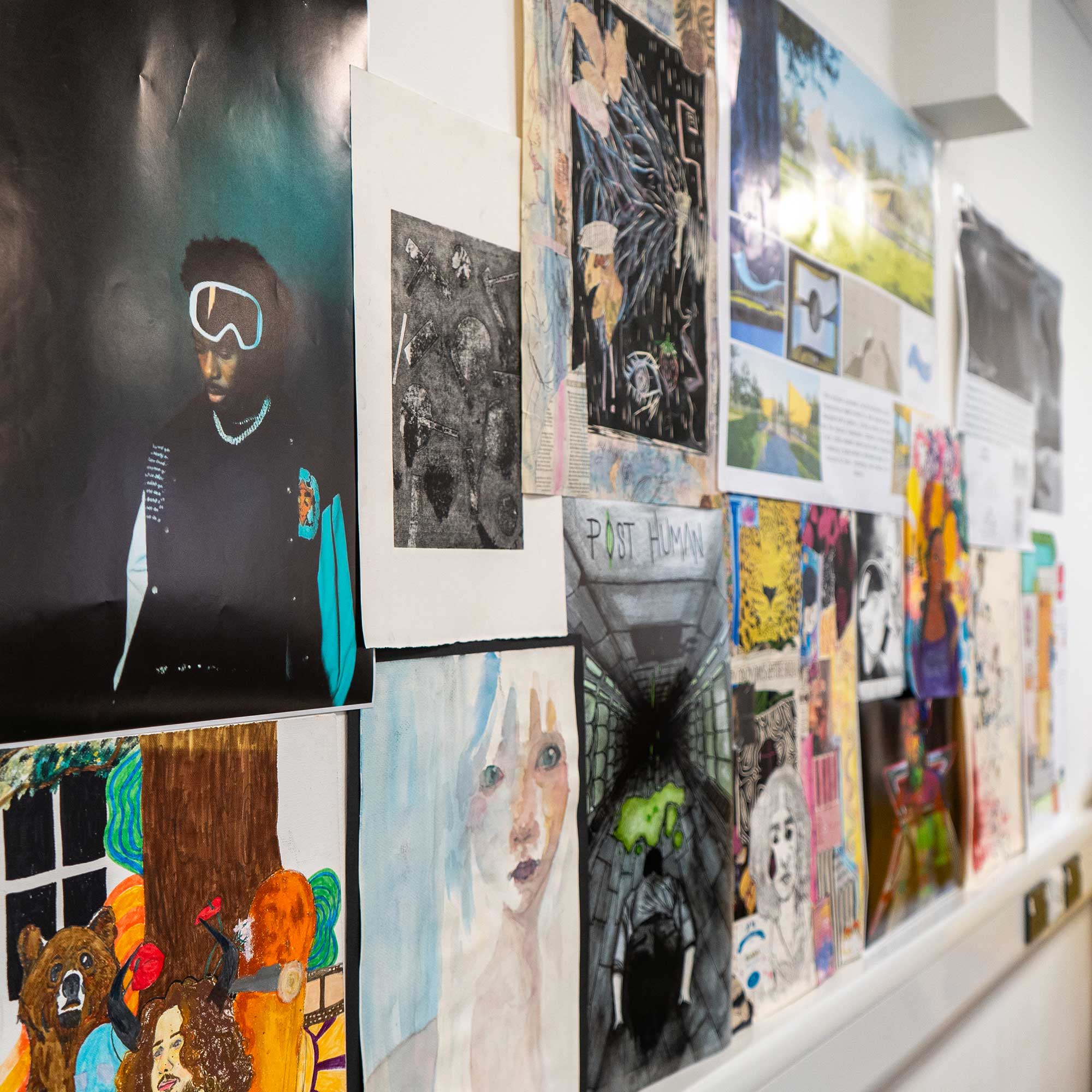 A collection of artwork on the wall including photography and drawings.