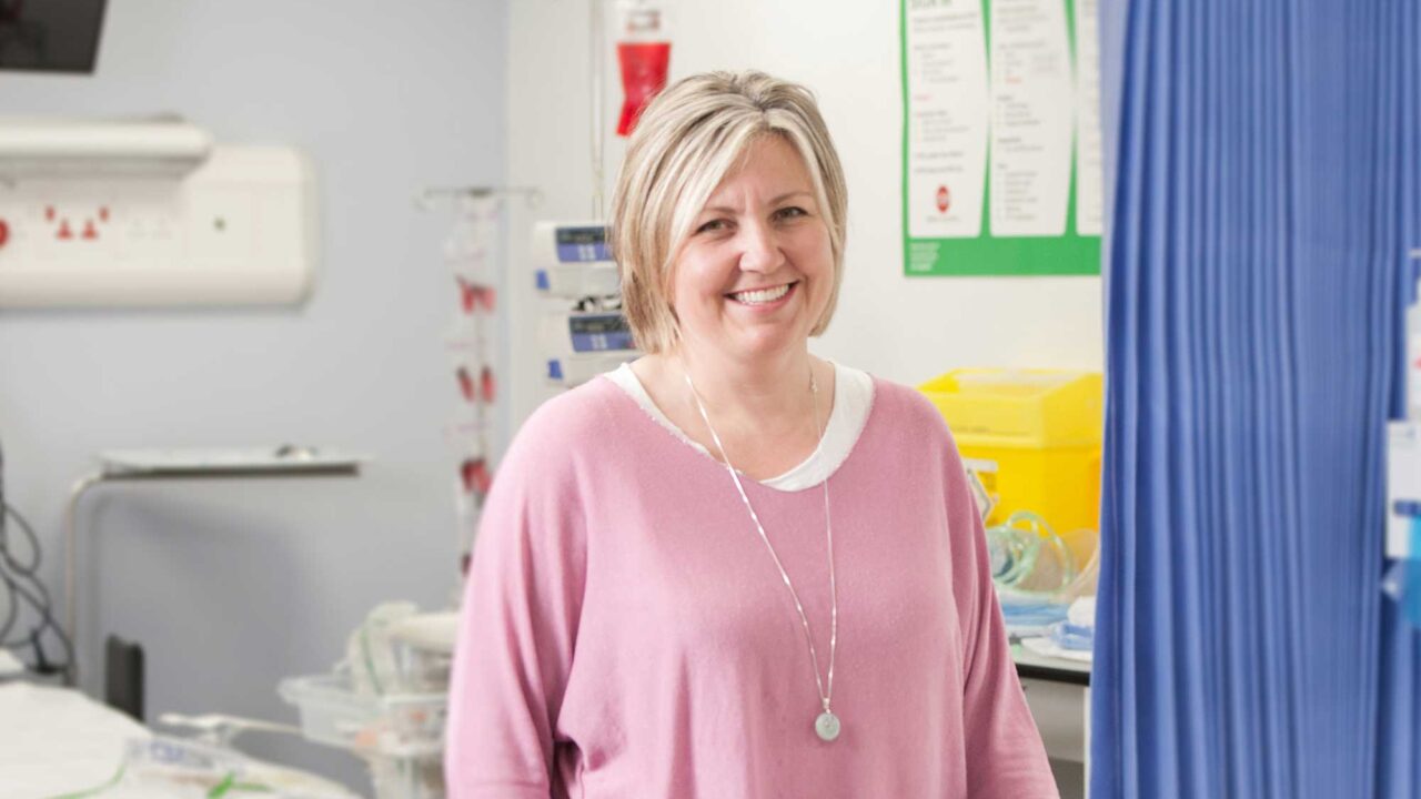 A postgraduate health and social care student standing in a hospital ward setting.