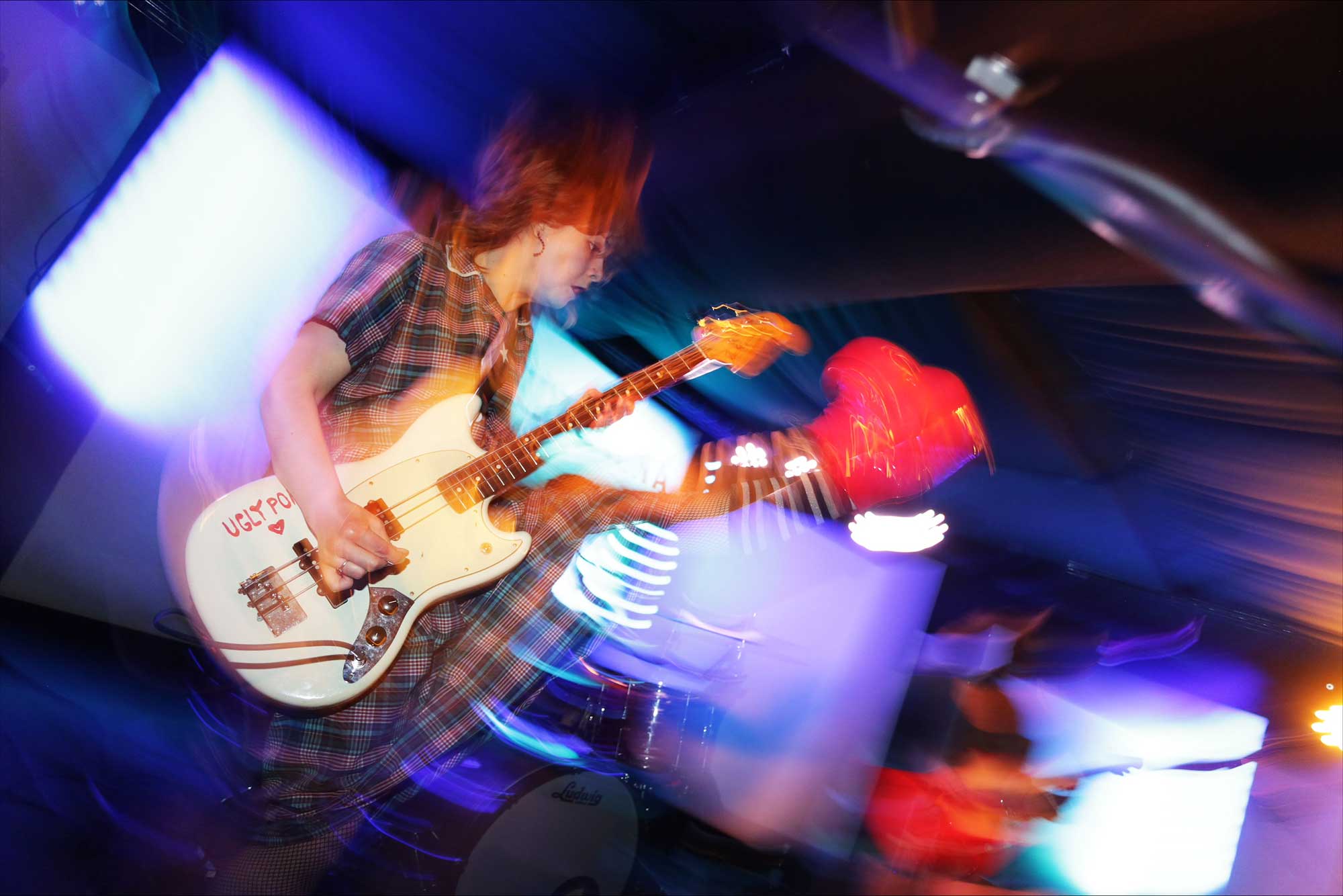 A blurred photo of a female musician on stage playing guitar.
