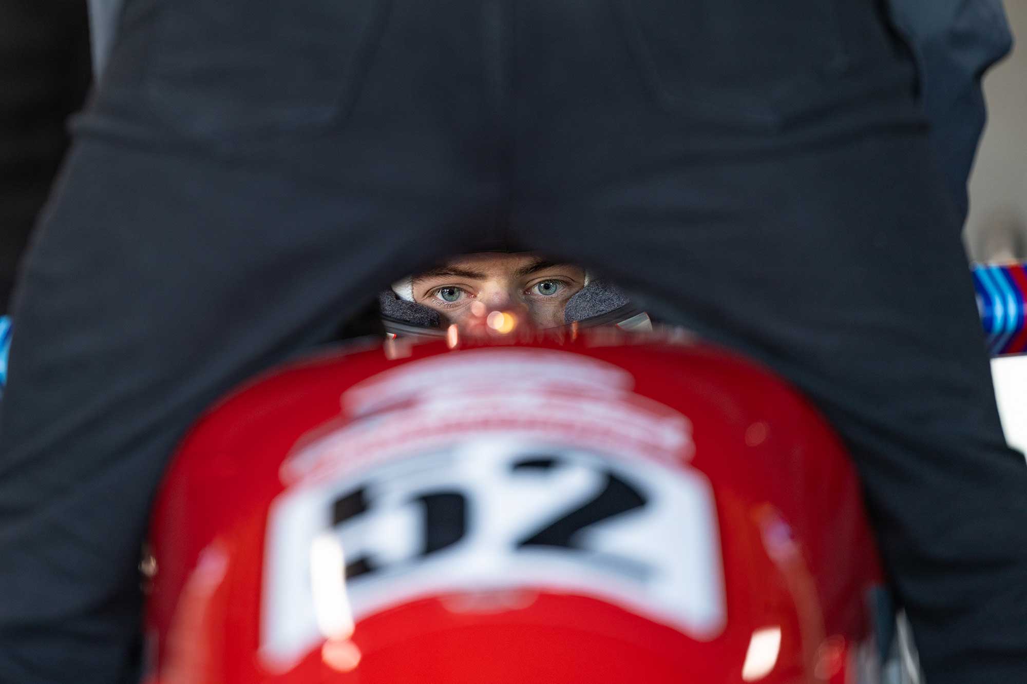 A racing driver looks into the camera while sitting in their racing car.