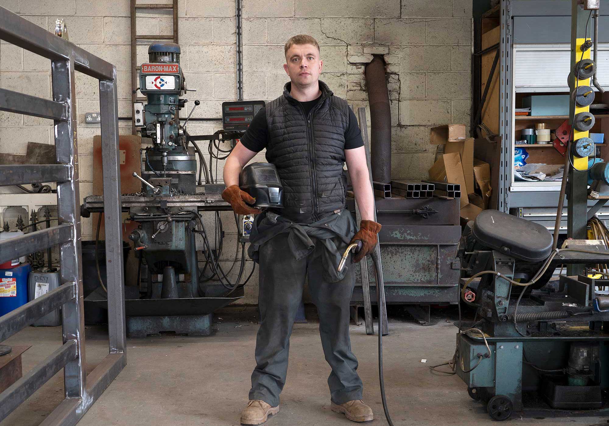 A man standing in a workshop surrounded by machinery.