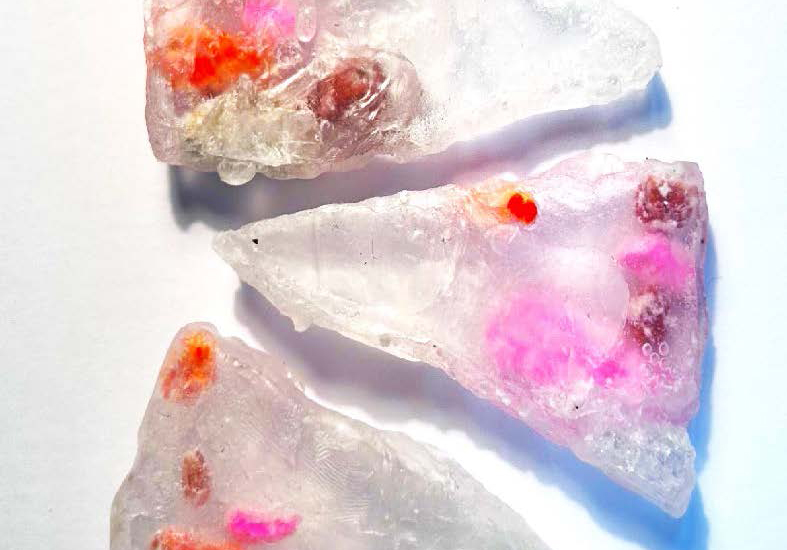 Triangular pieces of translucent material with coloured globules within.